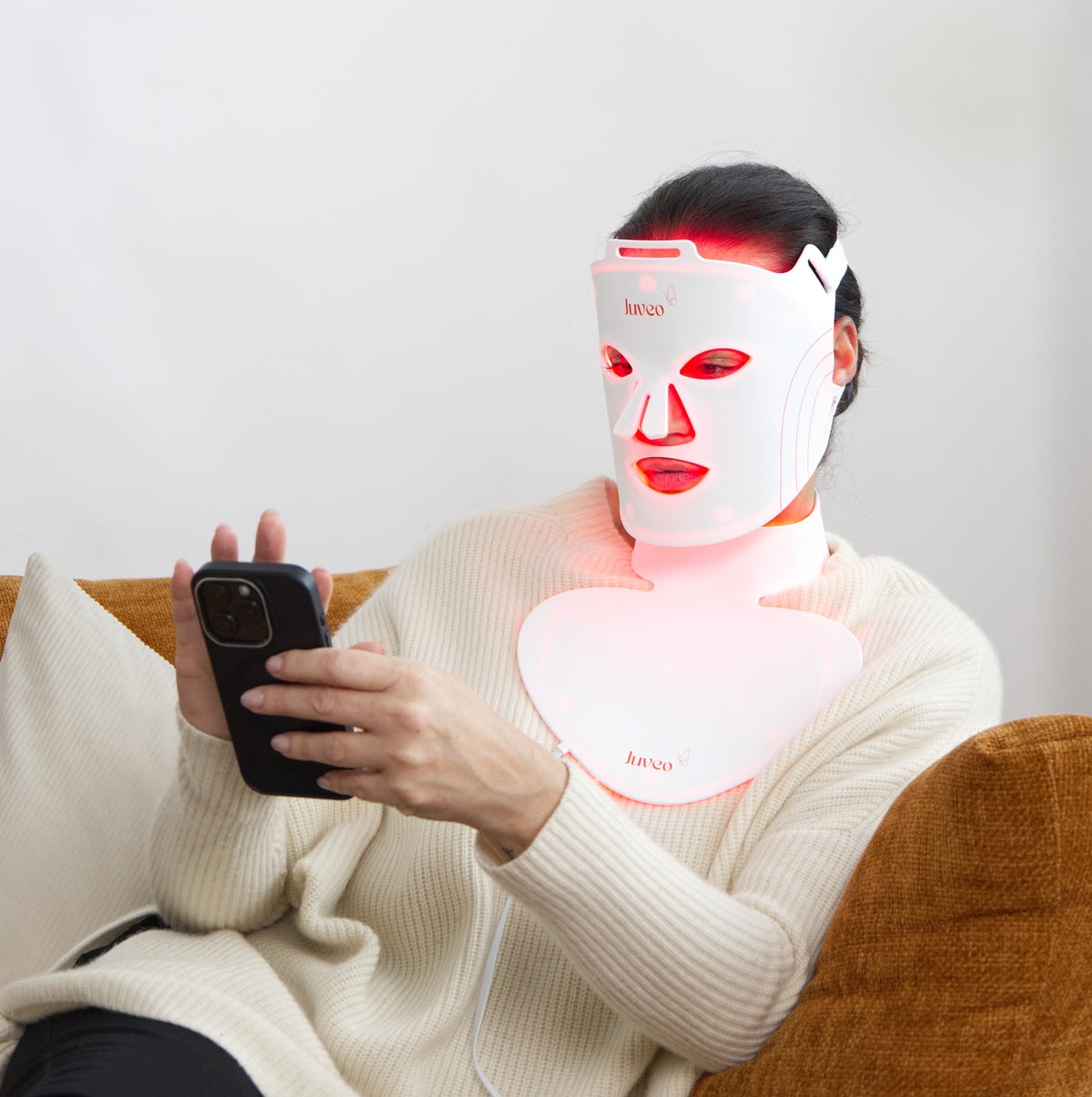 Woman using Juveo R1 LED therapy device at home