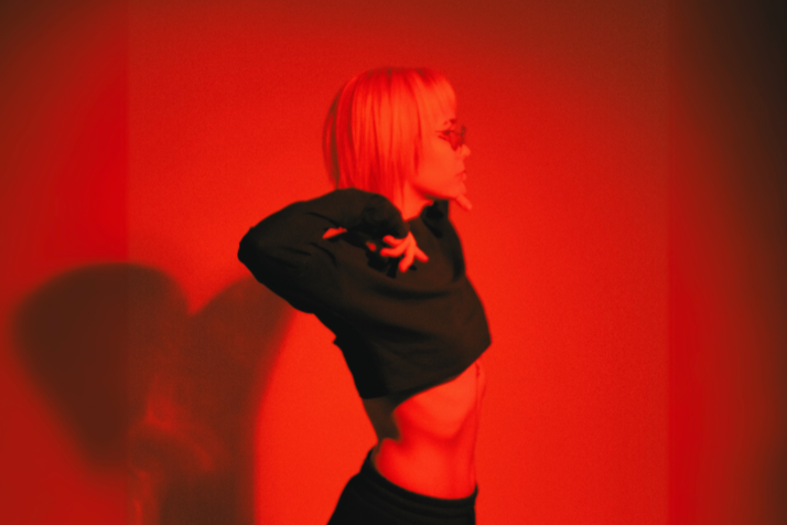 Woman lifting shirt under red light, exposing skin for light therapy treatment